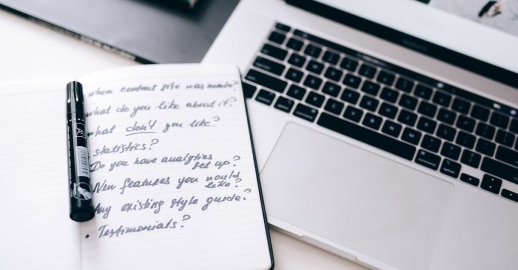 A notebook with handwritten notes next to a laptop on a workspace desk.