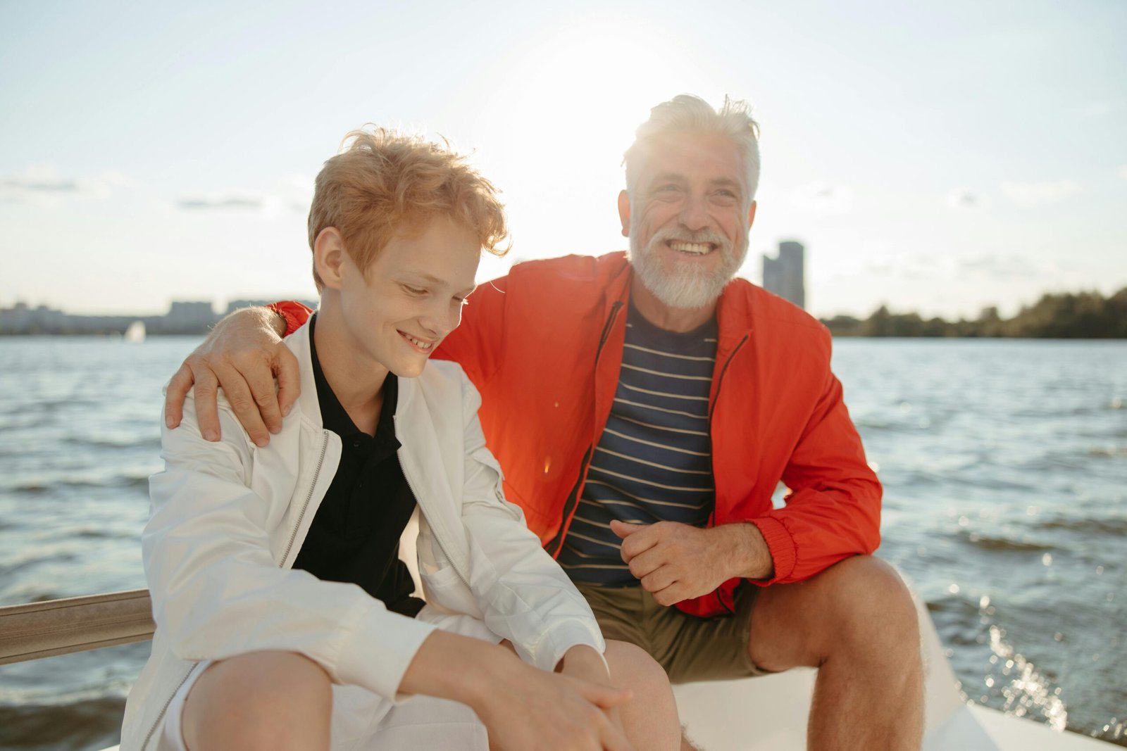 Smiling grandfather and grandson enjoy a sunny day on a boat, creating cherished memories.